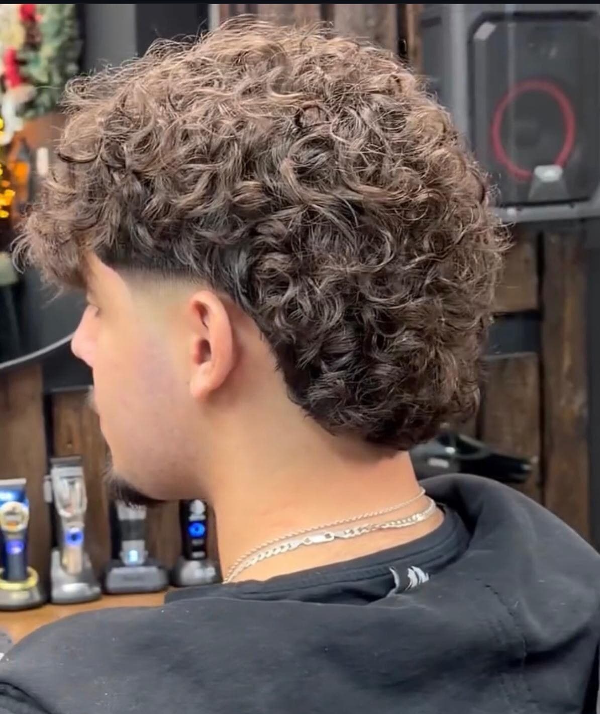 Curly hair on top with a low taper fade at the back and sides