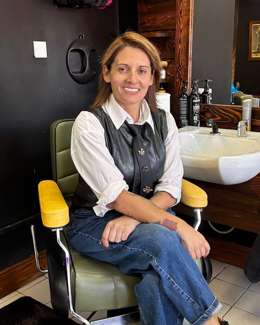 Lia, owner of The Urban Shave, sitting in a barber's chair in the shop
