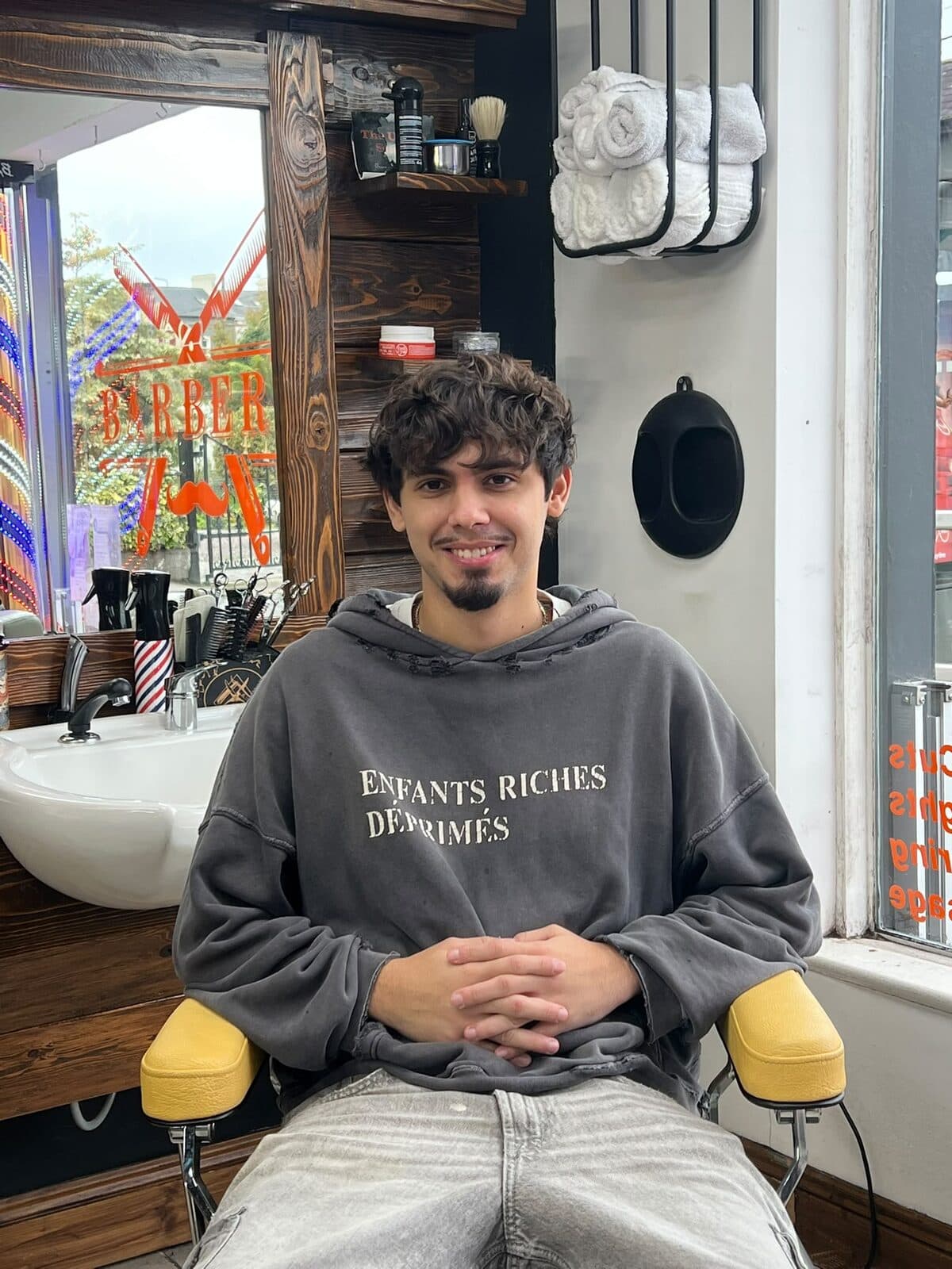 Max, barber at The Urban Shave, sitting in a barber's chair in the shop