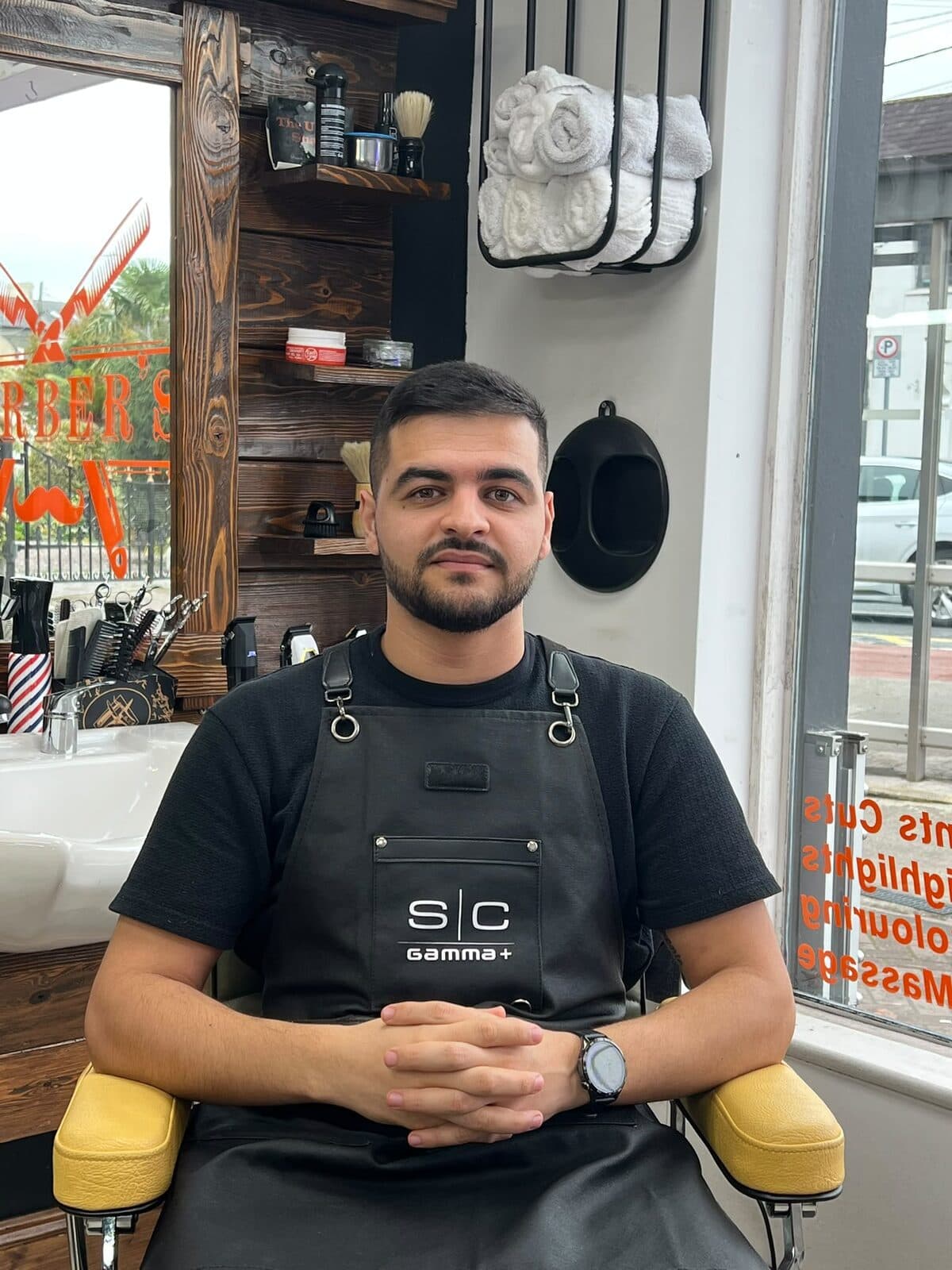 Metodi, barber at The Urban Shave, sitting in a barber's chair in the shop